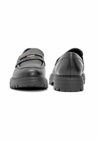 Czarne skórzane buty z płaską podeszwą, okrągłym noskiem i paskiem na wierzchu stopy. Charakteryzują się grubym, teksturowanym bieżnikiem na podeszwie oraz subtelnym przeszyciem.