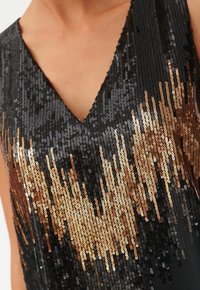 Top negro con lentejuelas y diseño de escote en V, que presenta un degradado de lentejuelas doradas a bronce creando un patrón brillante.