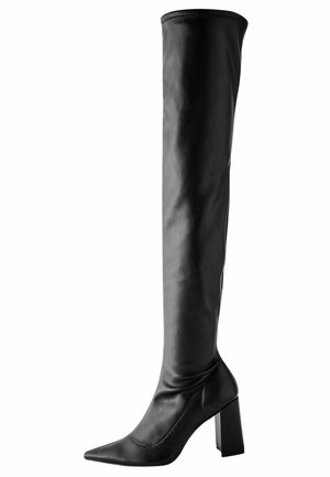 Vysoká černá kožená bota s špičatou špičkou a robustním vysokým podpatkem, sahající nad koleno.