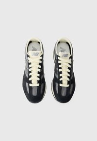 Black and gray sneakers with a suede upper, mesh panels, and cream laces. Features a rounded toe and logo on the tongue. Textured rubber sole.