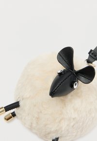 Skórzana torba w kształcie owcy, z puszystym kremowym ciałem, czarną skórzaną twarzą i okrągłymi, białymi oczami. Akcenty z złotego metalu.