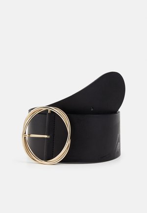 Ceinture en cuir noir avec une large lanière et une grande boucle ronde dorée, enroulée verticalement sur un fond blanc uni.