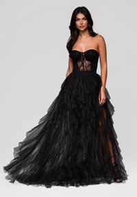 Svart strapless klänning med en åtsittande överdel med spetsdetaljer och en lager av tyl skör som faller till golvet.