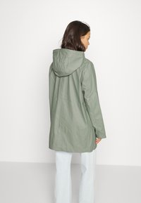 Langer, mit Kapuze versehenen Jacke aus gedämpftem grünem Stoff. Verfügt über einen geraden Schnitt und eine glatte Textur, mit einem schlichten Design und ohne sichtbare Beschläge.