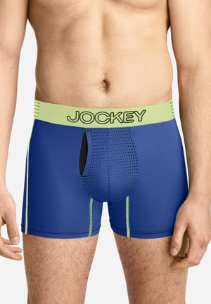 Male torso wearing blue boxer briefs with perforated front pouch and light green waistband labeled Jockey.