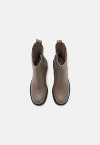 Bottes chevilles en cuir marron avec une texture lisse, dotées de fermetures éclair latérales et d'une semelle en caoutchouc noire, conçues pour un enfilage facile.
