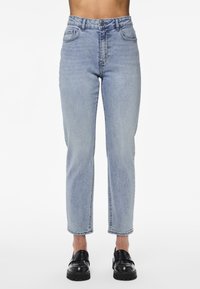 Vaqueros de mezclilla azul claro con cintura alta, corte recto, bolsillos frontales y un ligero desvanecimiento. Combinados con zapatos negros sin cordones.