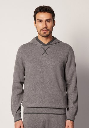 Grå strikket hoodie med V-halsdesign og blød tekstur. Har lange ærmer og en kontrastsyet detalje ved halsen.
