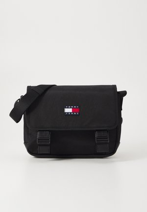 Bolsa mensajera negra Tommy Jeans con correa de hombro ajustable, solapa frontal y parche con el logo en rojo, blanco y azul.