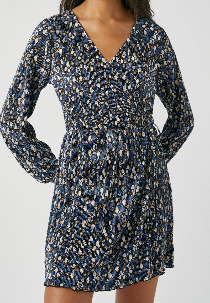 Kukkakuosiset kietaisumekot pitkillä hihoilla, jossa on sininen, valkoinen ja ruskea kuvio. Valmistettu teksturoidusta, laskostetusta kankaasta. V-pääntien muoto.