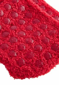 Röd texturerad matta med upphöjda cirkelmönster, tillverkad av mjukt material med en plyschkänsla och släta, glansiga accenter.