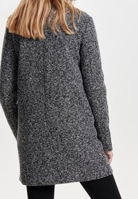 Cappotto grigio screziato con una texture morbida, maniche lunghe e taglio dritto, caratterizzato da una lunghezza fino a metà coscia e senza parti metalliche visibili.