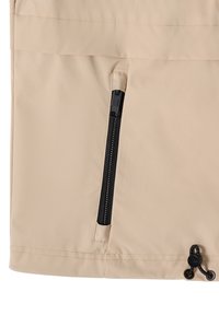 Tissu beige avec une poche à fermeture éclair noire verticale et un cordon de serrage réglable noir avec un toggle en bas à droite.