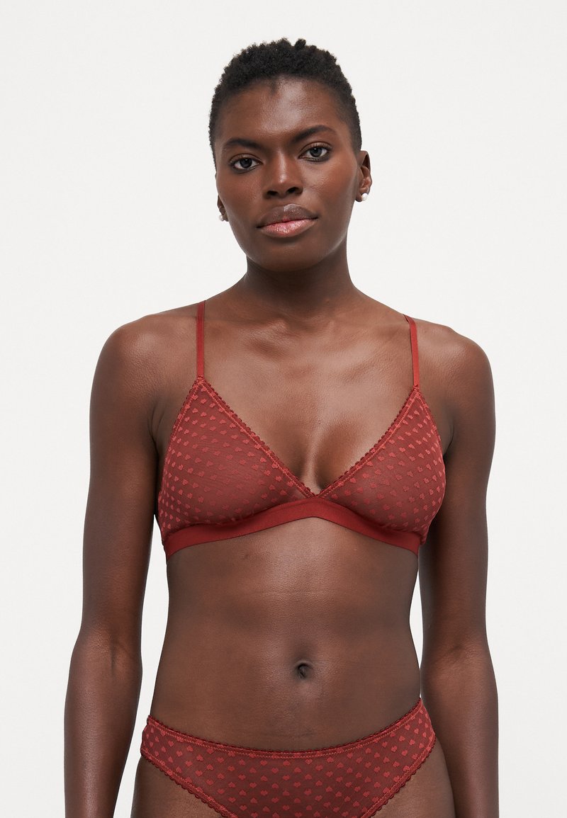 Rød, gjennomsiktig trekantet bralette med prikkete mønster, tynne stropper og blondedetaljer. Sammen med matchende truser. Mykt stoff og tettsittende design.