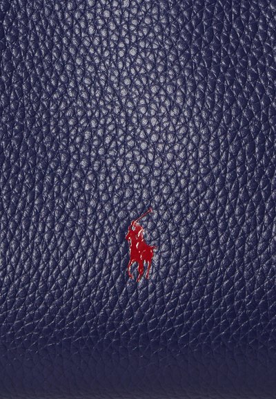 Laivastonsininen nahkapinta, jossa on tekstuuri, ja näkyvä punainen polo-pelaajan logo huomionarvoisena yksityiskohtana.