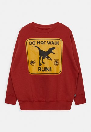 Rød sweatshirt med et gult skilt, der viser en sort dinosaursilhuet og teksten "DO NOT WALK RUN!" i fede sorte bogstaver.