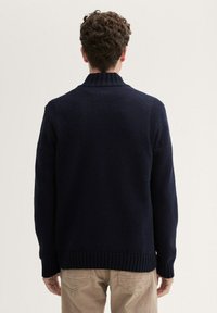 Navy gestrickter Pullover mit hohem Kragen, geripptem Material an den Bündchen und am Saum, lässiger Schnitt und glatter Oberfläche. Rückansicht gezeigt.