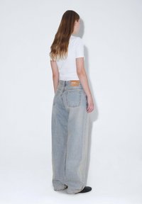 Ljust tvättade vida jeans med hög midja, som har en läderpatch bak, subtila slitningar och en rak silhuett.