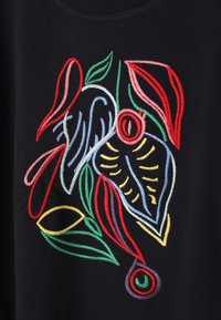 Feuilles et formes abstraites brodées colorées avec des fils rouges, verts, jaunes, bleus et violets sur un fond en tissu noir.