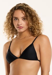Črn bikinski top v obliki trikotnika z nabranimi robovi, nastavljivimi naramnicami, gladko teksturo in minimalističnim dizajnom. Brez dodatnih okraskov.