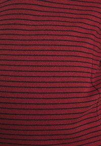 Tejido de punto a rayas rojas y negras con una textura suave. Las rayas están espaciadas de manera uniforme y corren horizontalmente a lo largo del material.