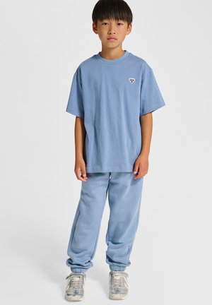 Hellblaues Baumwoll-T-Shirt und passende Sweatpants. Das T-Shirt hat ein kleines Motiv auf der Brust; die Hose ist mit elastischen Bündchen und einem lockeren Schnitt ausgestattet.