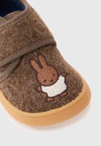 Chaussure pour tout-petit marron avec une semelle texturée et un lapin brodé portant une chemise blanche sur le bout.