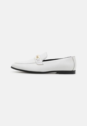 Mocassins en cuir blanc avec un bout arrondi, une sangle décorative, un accent doré et une semelle en caoutchouc noire. Fini lisse avec des détails de couture minimaux.