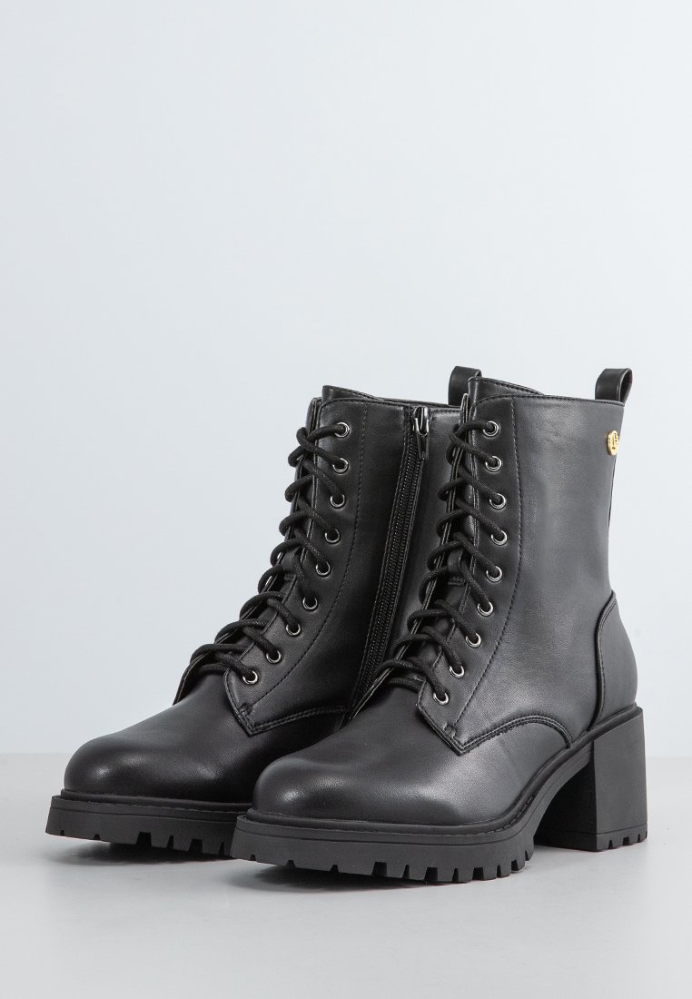 Schwarze Leder-Stiefeletten mit einem klobigen Absatz, Schnürung an der Vorderseite, seitlichem Reißverschluss und gummierter Profilsohle. Mit metallischem Akzent an der Seite.