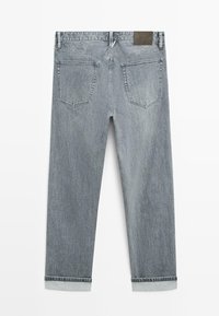 Jean en denim bleu clair avec une coupe droite, deux poches arrière, des détails cousus et une étiquette de marque marron sur la ceinture.