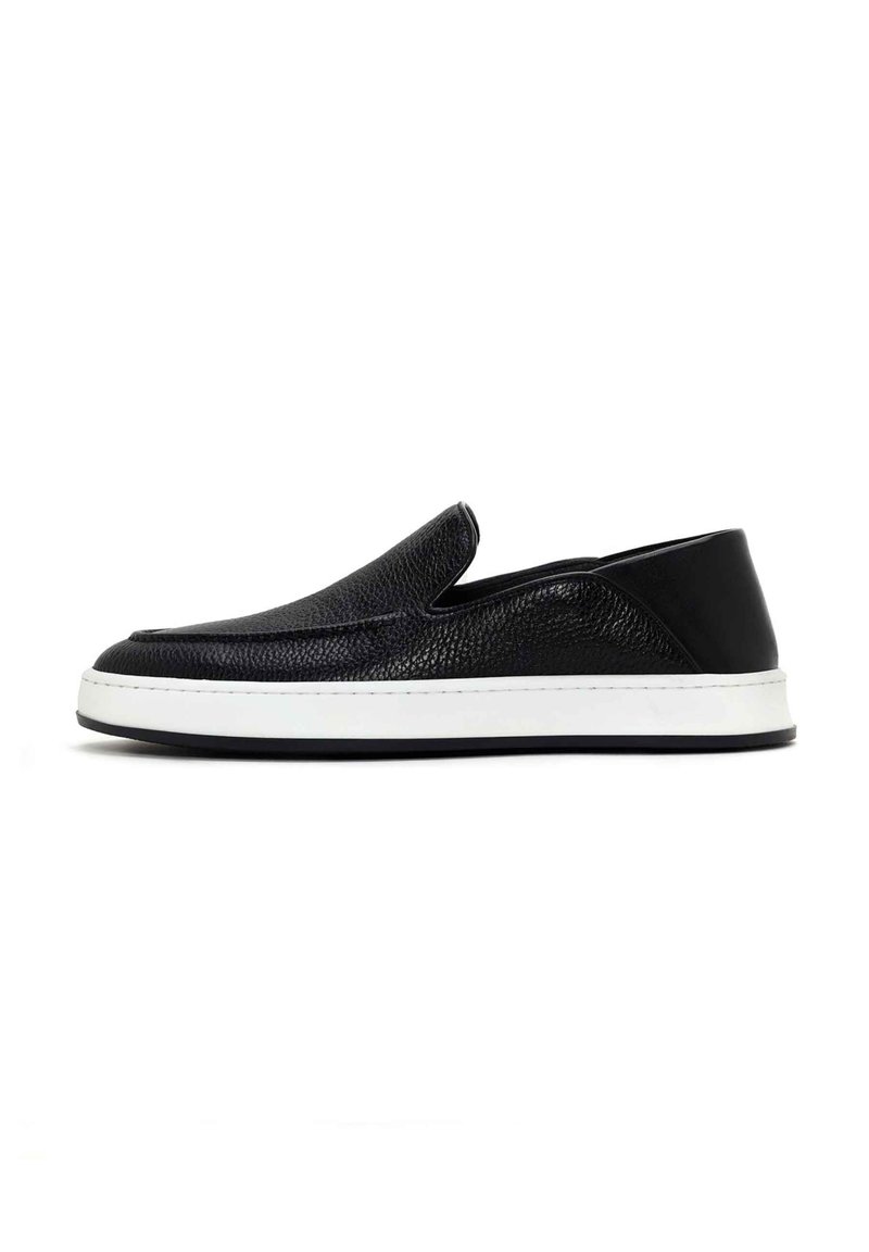 Black slip-on shoes made of textured leather with a white rubber sole, featuring a streamlined design and subtle stitching detail.