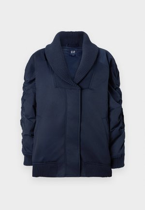 Veste bleu marine avec col châle à côtes, manchons froncés, poches avant, ainsi que des poignets et un ourlet à côtes, pliée à plat sur fond blanc.