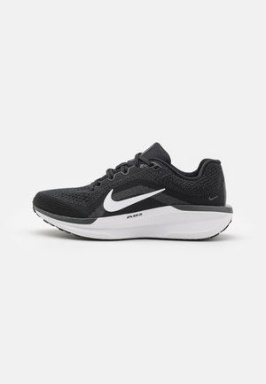 Chaussure de sport noire avec une tige en maille texturée, logo swoosh Nike blanc, semelle rembourrée et accents gris subtils sur la semelle intermédiaire.