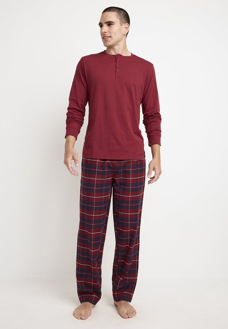 Red long-sleeve henley shirt with button placket paired with plaid pajama pants in dark red, navy, and white. Soft, relaxed fit.