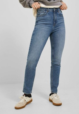 Hoch taillierte blaue Jeans mit schlanker Passform, aus Denim gefertigt. Verfügt über das klassische Fünf-Taschen-Design und dezente Ausbleichungen an den Beinen, kombiniert mit Sneakers.