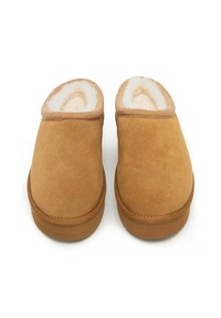 Zapatillas de ante color canela con un forro blanco suave, forma redondeada y borde cosido. Suela de goma que ofrece estabilidad y comodidad.