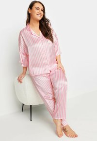 Conjunto de pijama de satén a rayas rosas y blancas que incluye una parte superior de botones de manga corta y pantalones a juego con un corte holgado y una textura suave.