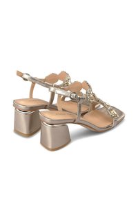 Sandali con tacco in metallo dorato, design con T-strap, decorazioni in perline, punta quadrata e tacco a blocco per stabilità.