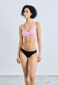 Bralette rose sans couture avec un design décolleté en V associé à un bas de bikini noir avec des bordures en dentelle, mettant en valeur une texture lisse et une coupe ajustée.