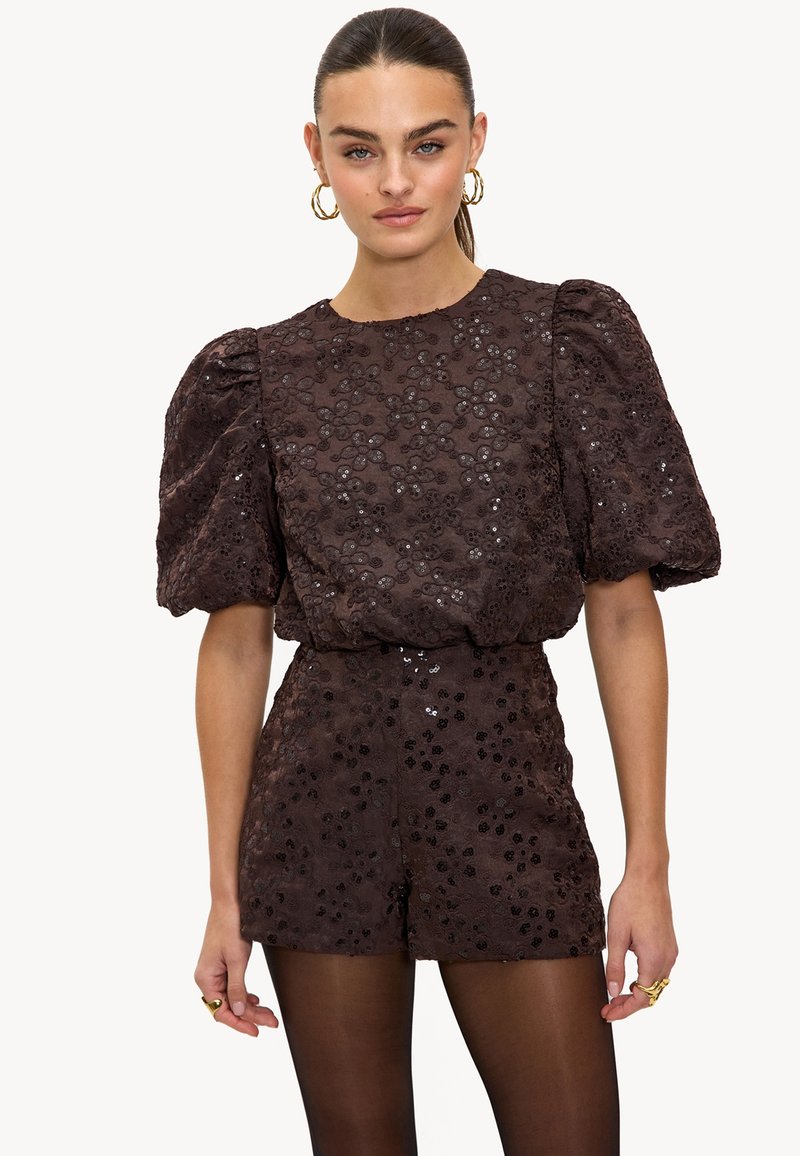 Rompers en dentelle florale marron avec des manches bouffantes, texture pailletée et taille cintrée. Comprend un short et un col rond.