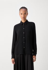 Black button-up shirt with a ribbed texture, collar, and long sleeves. Features silver buttons down the front and a relaxed silhouette.