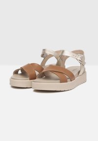 Sandali platform beige e argento metallizzato con cinghie incrociate, fibbia regolabile, suole imbottite e suola in gomma testurizzata.