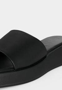 Μαύρο σανδάλι με λωρίδα και ελαφρώς ανυψωμένη σόλα, σχεδιασμένο για καθημερινή χρήση.