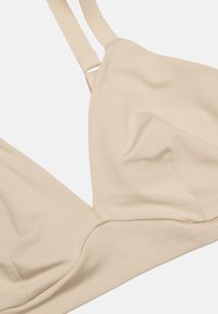 Beige trådlös bh med slät tyg, triangelkupor, justerbara band och sömlös design för komfort.