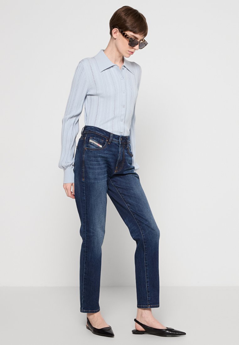 Camicia a righe azzurro chiaro con bottoni e maniche lunghe, abbinata a jeans dritti blu scuro e ballerine nere a punta.