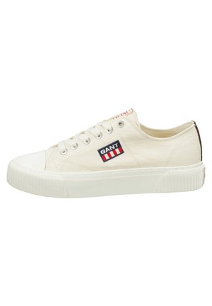 Canvas sneakers in cream with a white rubber toe cap and sole. Features a GANT logo patch with red and blue stripes. Low-top design.