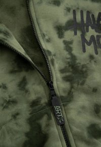 Oliwkowa bluza z kapturem na zamek z czarnym logo "HAVE MORE" oraz teksturowanym, miękkim materiałem z delikatnym wzorem tie-dye.