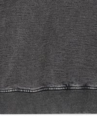 Tessuto grigio di felpa con un aspetto strutturato. Presenta un orlo a costine e una leggera sbiaditura lungo il bordo inferiore. Design semplice e casual.