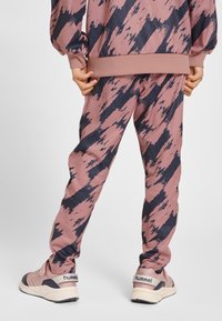 Rosa och marinblå randig träningsdräkt med elastiska muddar och avsmalnad passform. Tyget har en slät textur med ett mönstrat design.