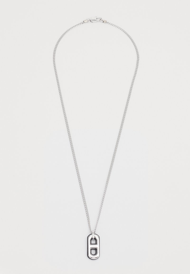 Hõbedane kaelakee, millel on kett ja ovaalne ripats, mis on kaunistatud lõigatud geomeetriliste kujunditega ja sileda pinnaviimistlusega.